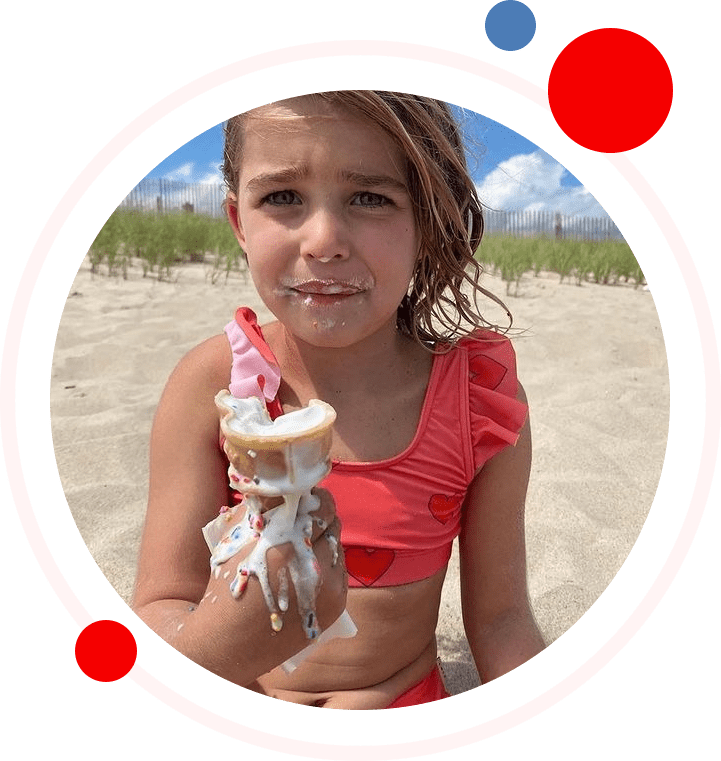 A girl holding an ice cream cone on the beach.